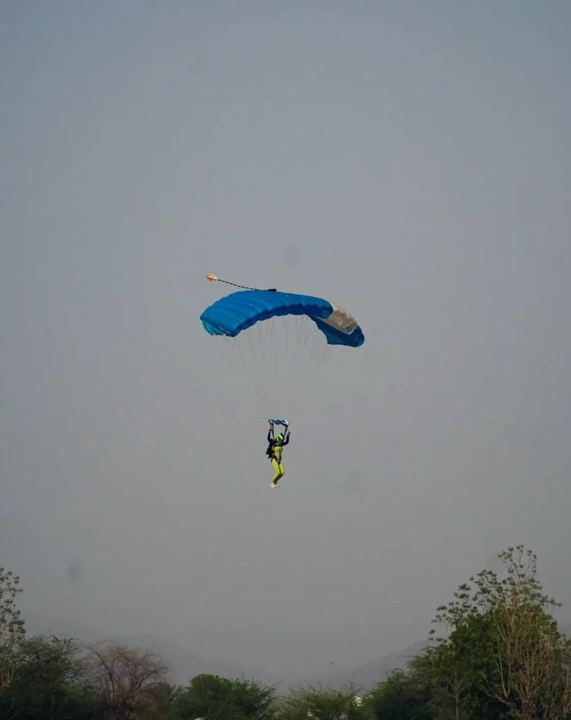A skydiver under a blue canopy coming in to land.